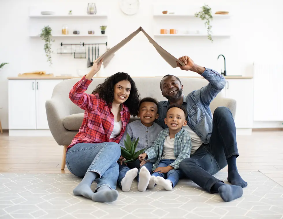 Des parents et leurs deux garçons, assis dans leur salon, dessinent un toit au-dessus d'eux — l'étude gratuite à faire avant d'hypothéquer sa maison