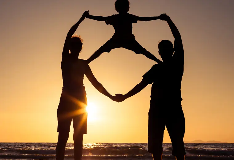 La silhouette de deux parents qui se donnent la main, leur enfant suspendu entre eux, au bord de l'eau — le prêt personnel, alternative à l'hypothèque