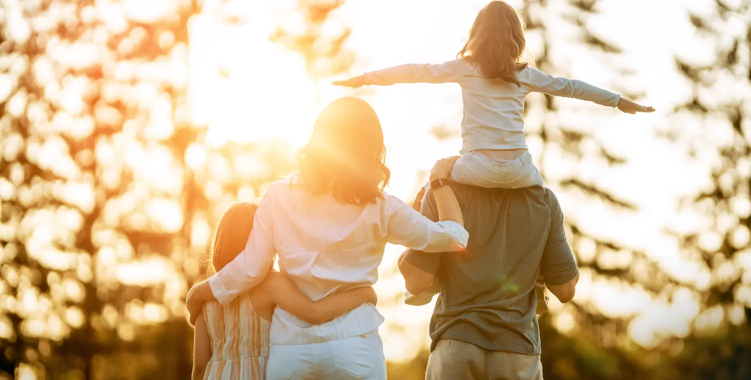 Une famille de dos regarde le jour tomber, la fille assise sur les épaules de son père, en tête du guide « Pourquoi hypothéquer sa maison »