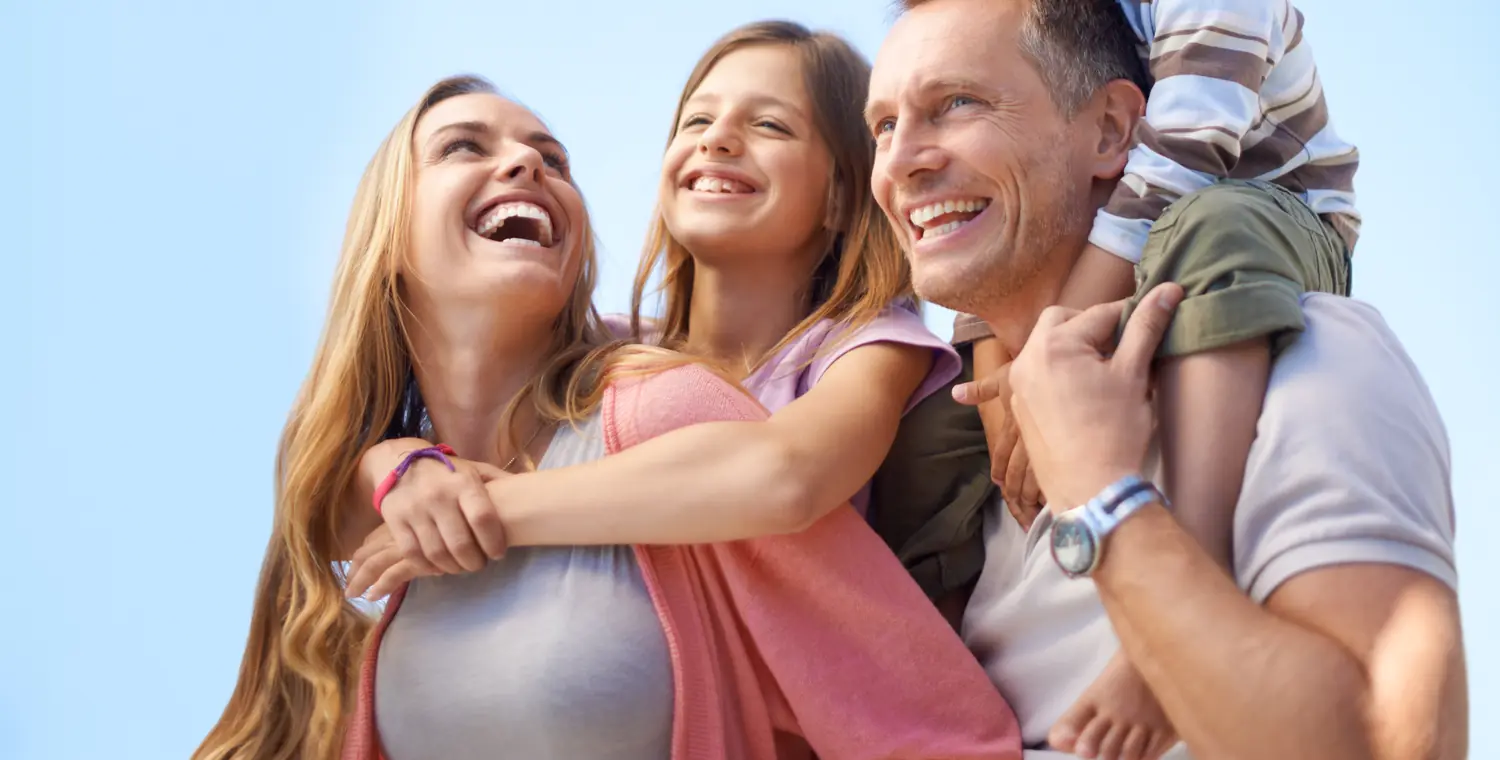 Une famille de quatre, serrée les uns contre les autres, rit sous un ciel dégagé, en tête du guide « Alternatives à l'hypothèque »